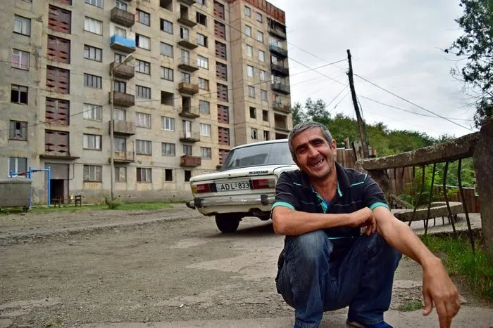 Arriba me esperan edificios en estado de medio abandono, gallinas y cerdos sueltos y este hombre con su coche que tiene más años que yo. 