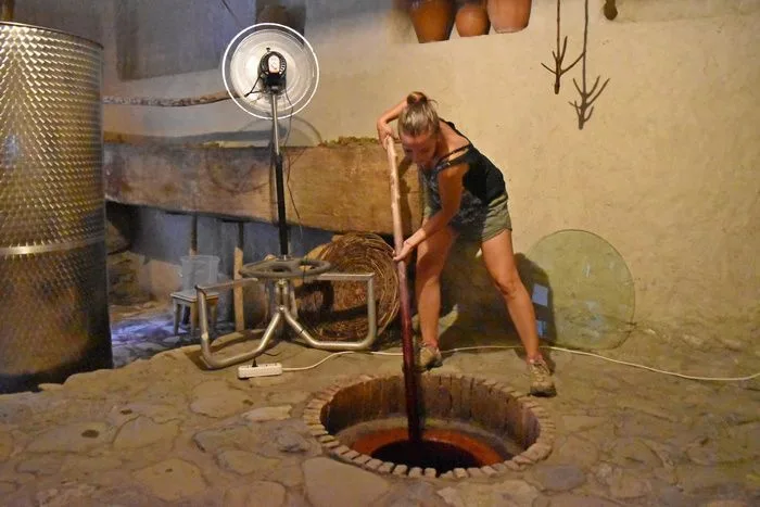 Removiendo la mezcla de chacha y zumo de uva que poco a poco se convertirá en vino. 