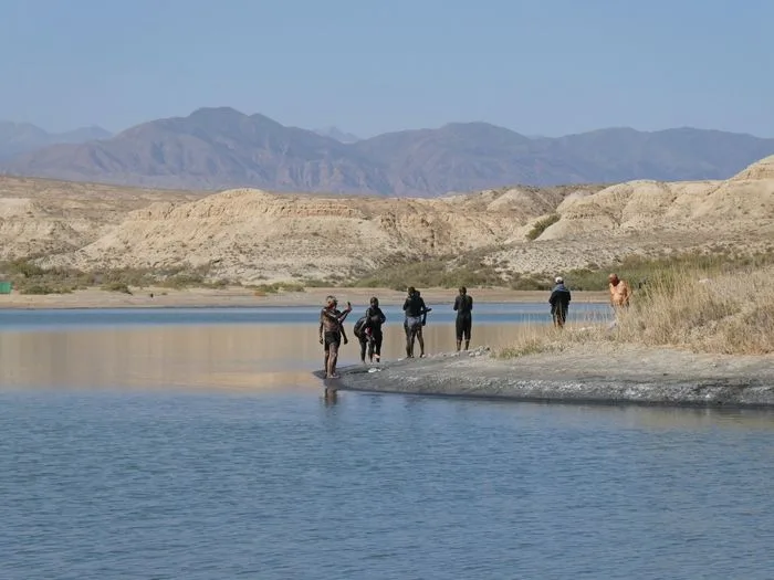 Locales con Barro negro por el cuerpo en el lago salado cerca de Kyzyl Tuu