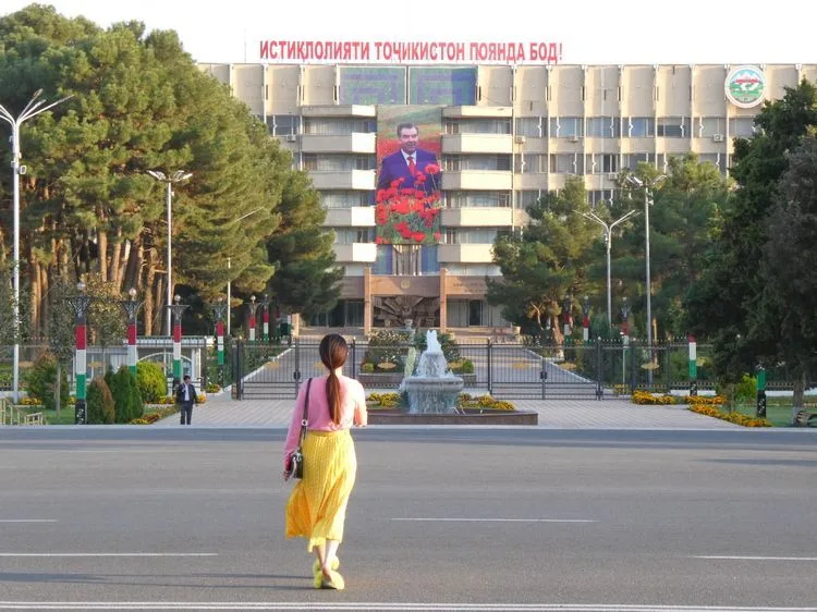 El omnipresente presidente Emomali Rahmon en un edificio en Khojand con una local vestida bastante colorida